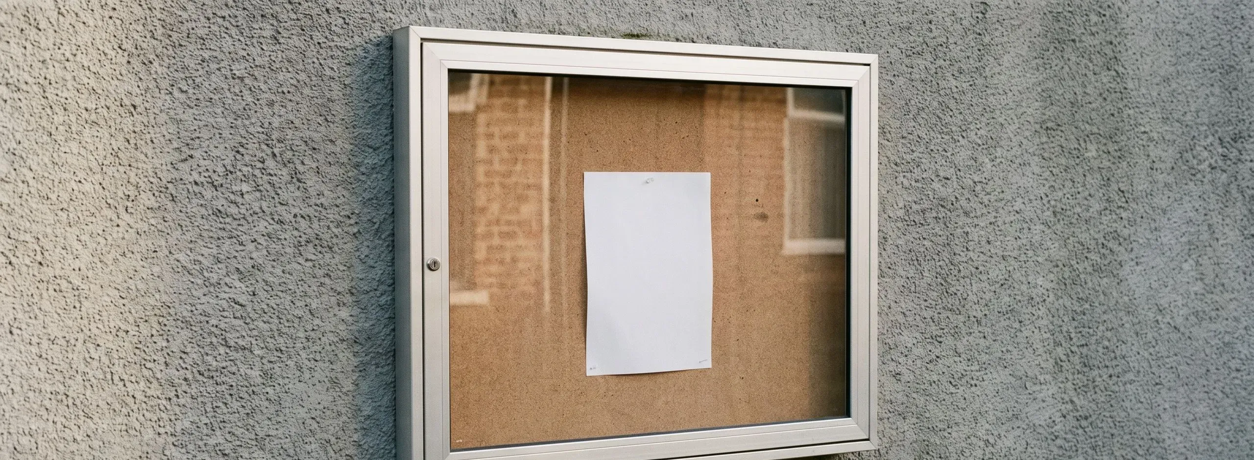 Verglaster Schaukasten an einer Wand mit einem einzelnen Aushang