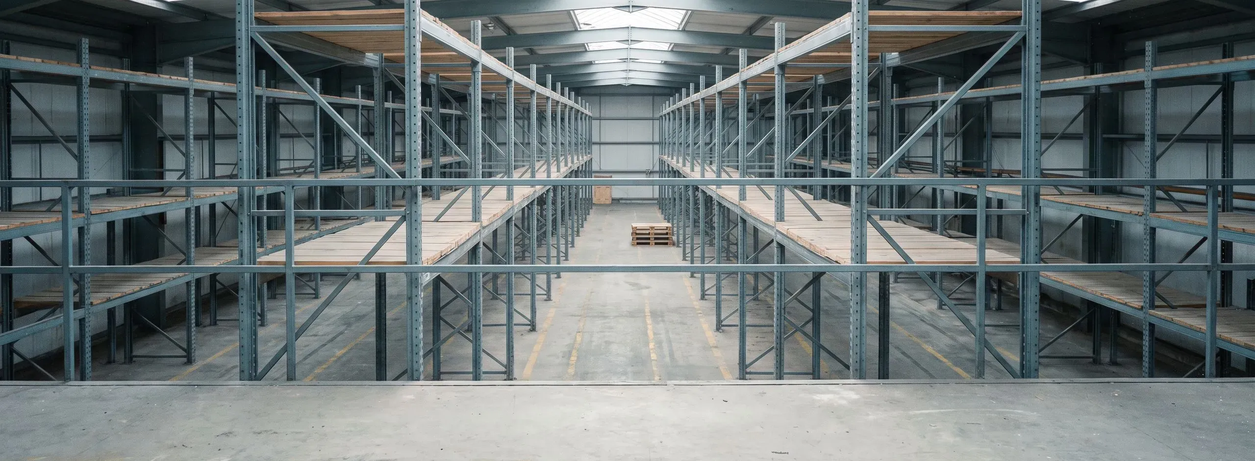 Leere Palettenregale beidseits eines Gangs in einer Lagerhalle