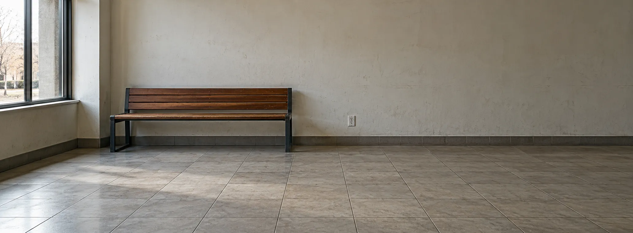 Empty waiting area with a wooden bench, large windows and a wall socket